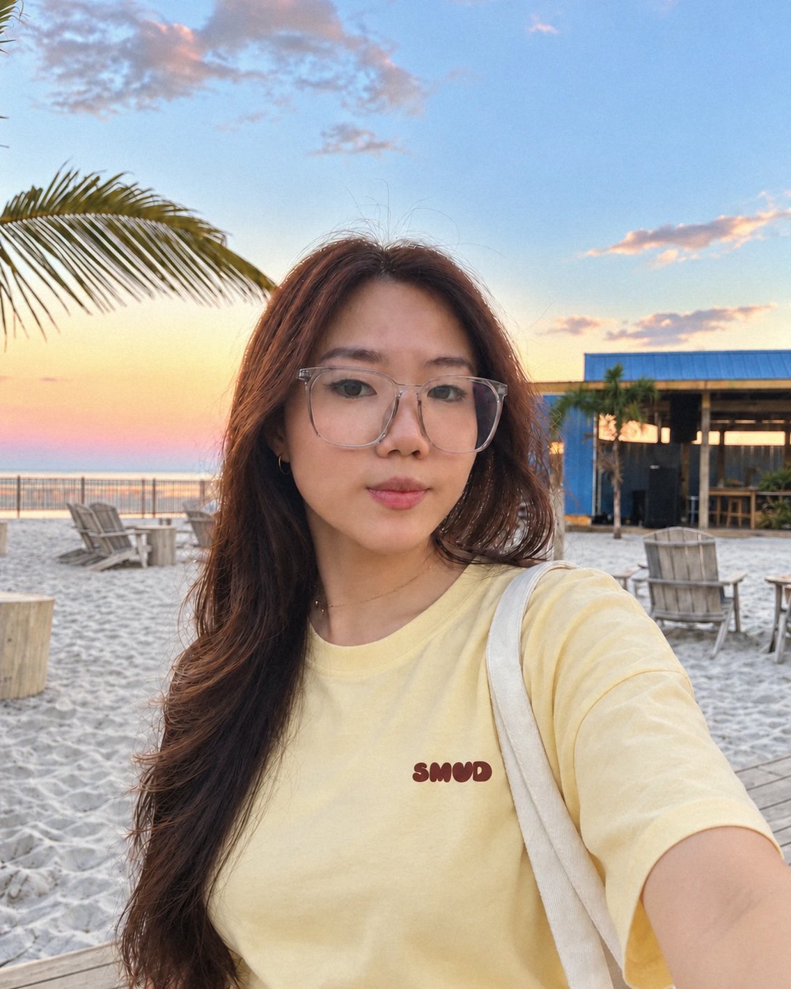 Vanessa, SMUD's founder, on the beach at sunset in a butter-yellow SMUD t-shirt